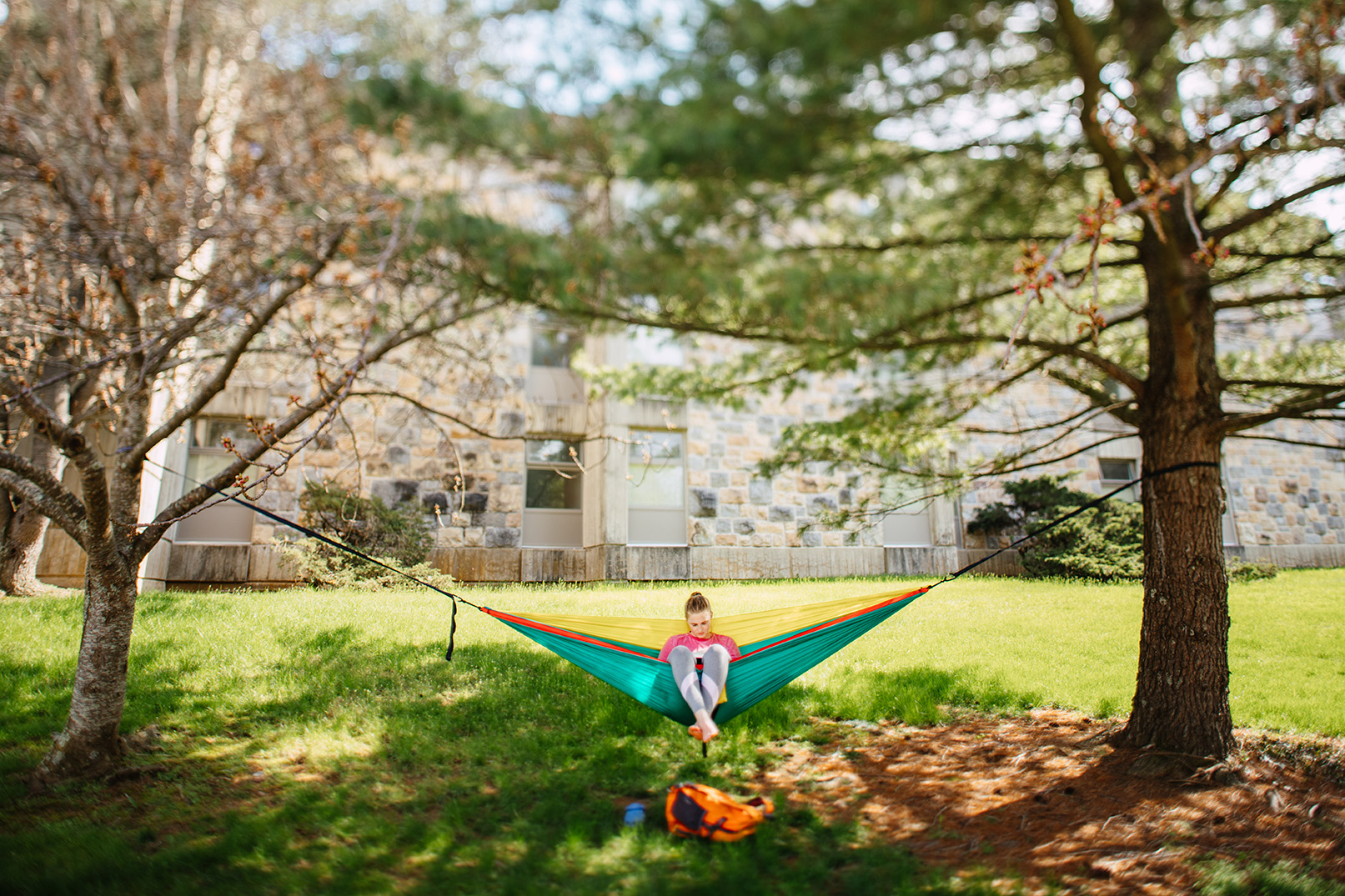 Virginia Tech’s campus shows off early spring blooms as a person sits in a hammock set up between two trees. (Photo by Christina Franusich/Virginia Tech)